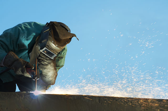 Welder grinding steel outdoors on a job site